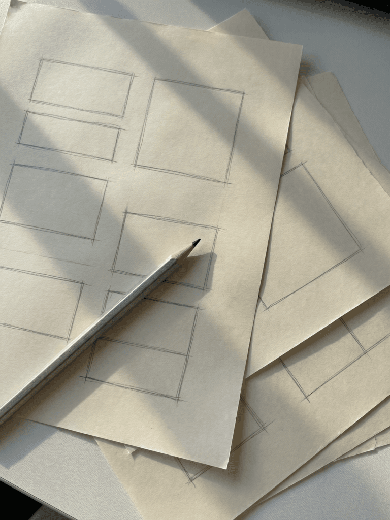 A pencil resting on paper sketched with page layout wireframes